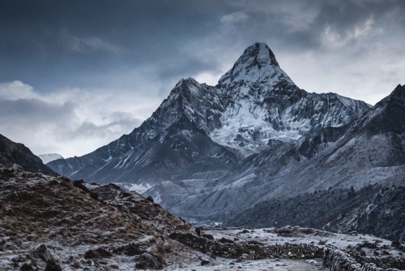 Ama Dablam's sharp summit spire and the hanging glacier beneath it, seen from the valley floor at dawn.