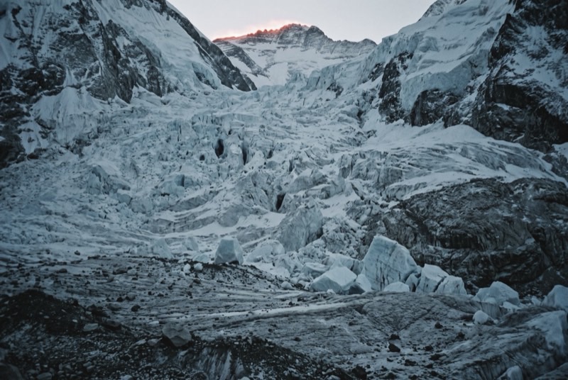 The Khumbu Icefall at dawn, empty of people, its seracs and crevasses tumbling from the Western Cwm under a thin band of sunrise on the ridge above.